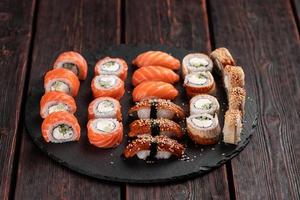 sushi reeks van top Aan zwart achtergrond detailopname. een assortiment van divers maki nigiri en broodjes zeevruchten soja saus foto