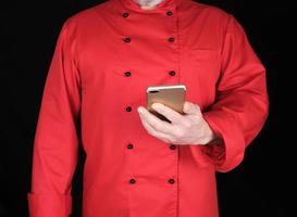 chef in rood uniform houdt in zijn hand- een smartphone foto