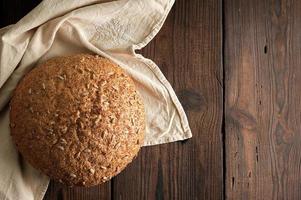 gebakken ronde rogge brood met zonnebloem zaden Aan een beige textiel servet foto