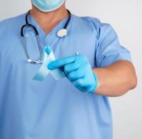 dokter in uniform en latex handschoenen Holding een blauw lint in zijn hand- foto