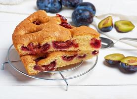 plakjes van biscuit Pruim taart Aan een wit houten bord en vers fruit foto