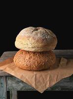 twee broden van gebakken ronde brood leggen Aan bruin papier foto