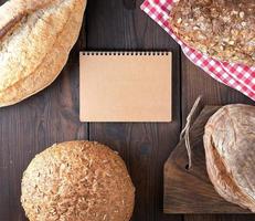 Open kladblok met leeg bruin lakens en gebakken brood broodjes foto