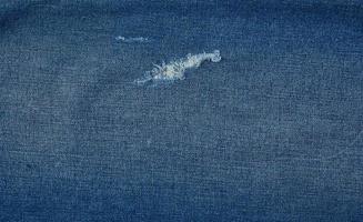 fragment van blauw jeans kleding stof met een gat, vol kader foto