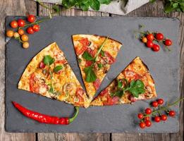 driehoekig stuk van gebakken pizza met paddestoelen, gerookt worstjes, tomaten foto