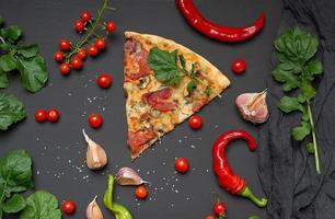 driehoekig plak van gebakken pizza met paddestoelen, gerookt worstjes, tomaten en kaas, De volgende naar vers groen bladeren van rucola foto