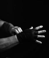 Mens wraps zijn handen in zwart textiel verband voor sport- foto