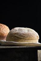 gebakken ronde wit tarwe brood Aan een textiel handdoek, houten oud tafel foto
