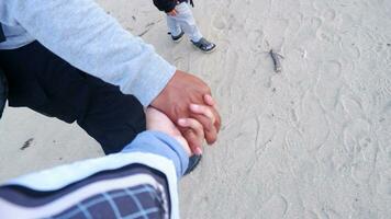 een paar wandelen Holding handen Aan de strand met een achtergrond van strand zand foto