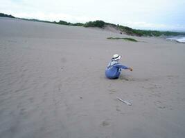 terug van de vrouw in de hoed wie was zittend en spelen strand zand, de visie van de zand foto