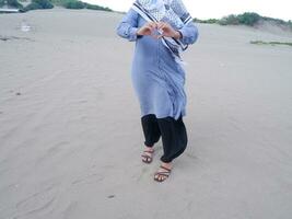 voor de helft de lichaam van de vrouw in blauw stond Aan de strand zand en haar handen gevormd liefde foto