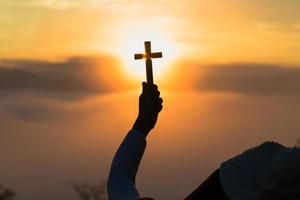 silhouet van vrouw bidden met kruis in natuur zonsopkomst achtergrond, kruisbeeld, symbool van vertrouwen. christen leven crisis gebed naar god. foto