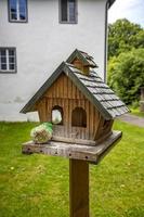 houten klein huis en vogel voeder Bij de tuin. leeg vogelhuisje handgemaakt van hout buitenshuis foto