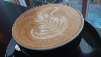 dichtbij omhoog schot van capuchino kunst in een zwart koffie kop foto