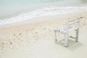 witte houten stoel aan zee foto