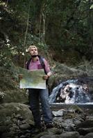 avontuurlijke man observeren kaart op een bergpad foto