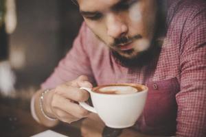 jonge man zit in een café en een kopje koffie drinken