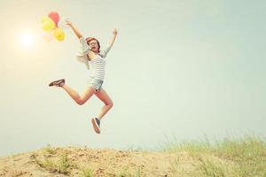 mooi meisje springen met ballonnen op het strand foto