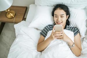 jonge vrouw met behulp van haar smartphone op bed foto