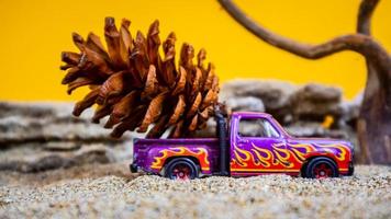 speelgoed- auto vervoeren dennenappels Aan een oranje achtergrond foto