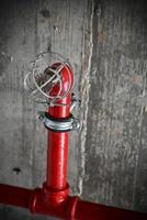 een detail van een rustiek plafond met rood pijpen en een brand alarm foto