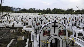 de openbaar begraafplaats bevat identiek wit keramisch graven met bloemen. foto