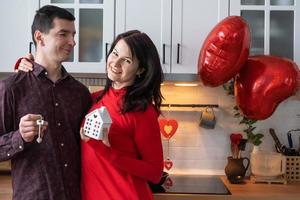 Mens en vrouw in liefde datum Bij huis in keuken met sleutels van huis. Valentijnsdag dag, gelukkig stel, liefde verhaal. liefde nest, hypotheek, verhuizing, aankoop, echt landgoed, behuizing voor jong familie foto