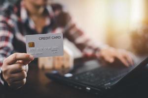 vrouw Holding credit kaart voor maakt een aankoop Aan de internet Aan de laptop computer met credit kaart, online betaling, boodschappen doen online, e-commerce, internet bankieren, uitgeven geld concept. foto