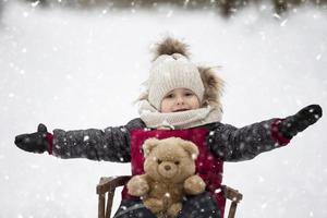 een weinig jongen zit in een houten slee tegen de backdrop van winter natuur. foto