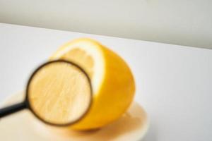 geel gesneden citroen met vergrootglas Aan wit tafel foto