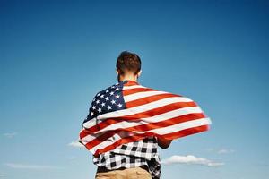 Mens houdt Verenigde Staten van Amerika nationaal vlag tegen blauw lucht foto