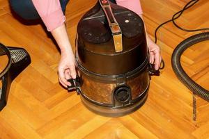 een middelbare leeftijd vrouw verzamelt een vacuüm schoonmaakster voor huis schoonmaak. foto