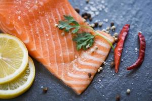 vers Zalm filet Aan donker achtergrond dichtbij omhoog van rauw Zalm vis zeevruchten met citroen kruiden en specerijen foto