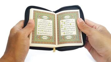 Mens lezing de heilig koran. hand- Holding een heilig koran Aan wit achtergrond. foto