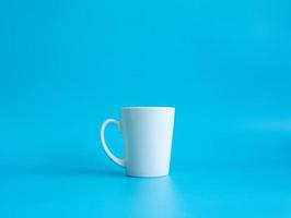 wit koffie kop top visie fotograaf Aan een wit schotel de binnen van de glas looks leeg. aan het wachten voor heet koffie naar worden bijgevuld naar drinken naar voelen verfrist en alarm Aan een blauw achtergrond. foto