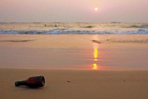 zonsondergang strand met een bier fles foto