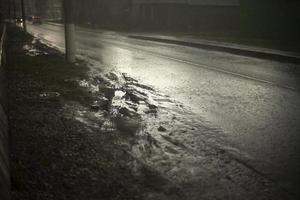 nat weg in regen. plas Aan snelweg. vuil langs de weg. foto