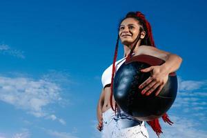 achtergrond lucht. atletisch vrouw met med bal. sterkte en motivatie.foto van sportief vrouw in modieus sportkleding foto