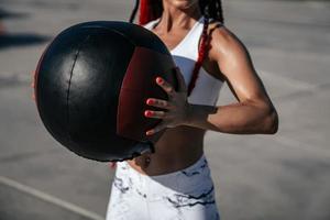 handen dichtbij omhoog. atletisch vrouw met med bal. sterkte en motivatie.foto van sportief vrouw in modieus sportkleding foto