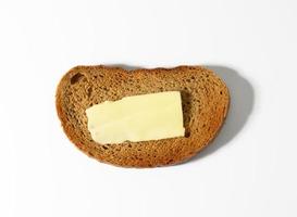 ovaal plak van rogge meel brood, een plak van boter Aan top foto