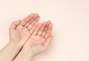 twee vrouw handen gevouwen palm naar palm Aan een beige achtergrond foto