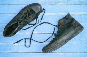 paar- van zwart oud haveloos sportschoenen met losgemaakt veters foto