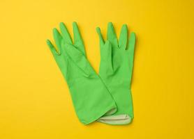 paar- van groen beschermend rubber handschoenen voor schoonmaak Aan een geel achtergrond foto
