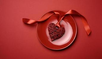 gevlochten hart met zijde lint in rood keramisch bord foto