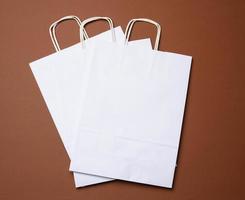 wit papier beschikbaar zak met handvatten Aan een bruin achtergrond foto