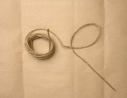 bruin gevouwen touw Aan een bruin papier achtergrond, touw voor huishouden behoeften foto