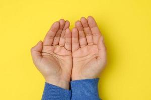 twee vrouw handen gevouwen palm naar palm Aan een geel achtergrond foto