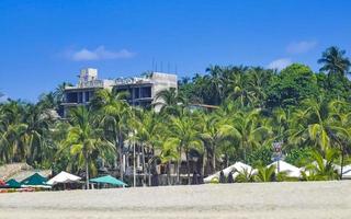 palmen parasols zon ligstoelen strand golven puerto escondido Mexico. foto