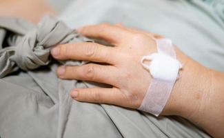 vrouw hand- geven zoutoplossing oplossing in bed in ziekenhuis. foto