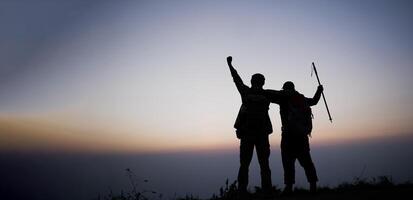 silhouet van juichen wandelen mannen Open armen naar de zonsopkomst staan Aan berg foto